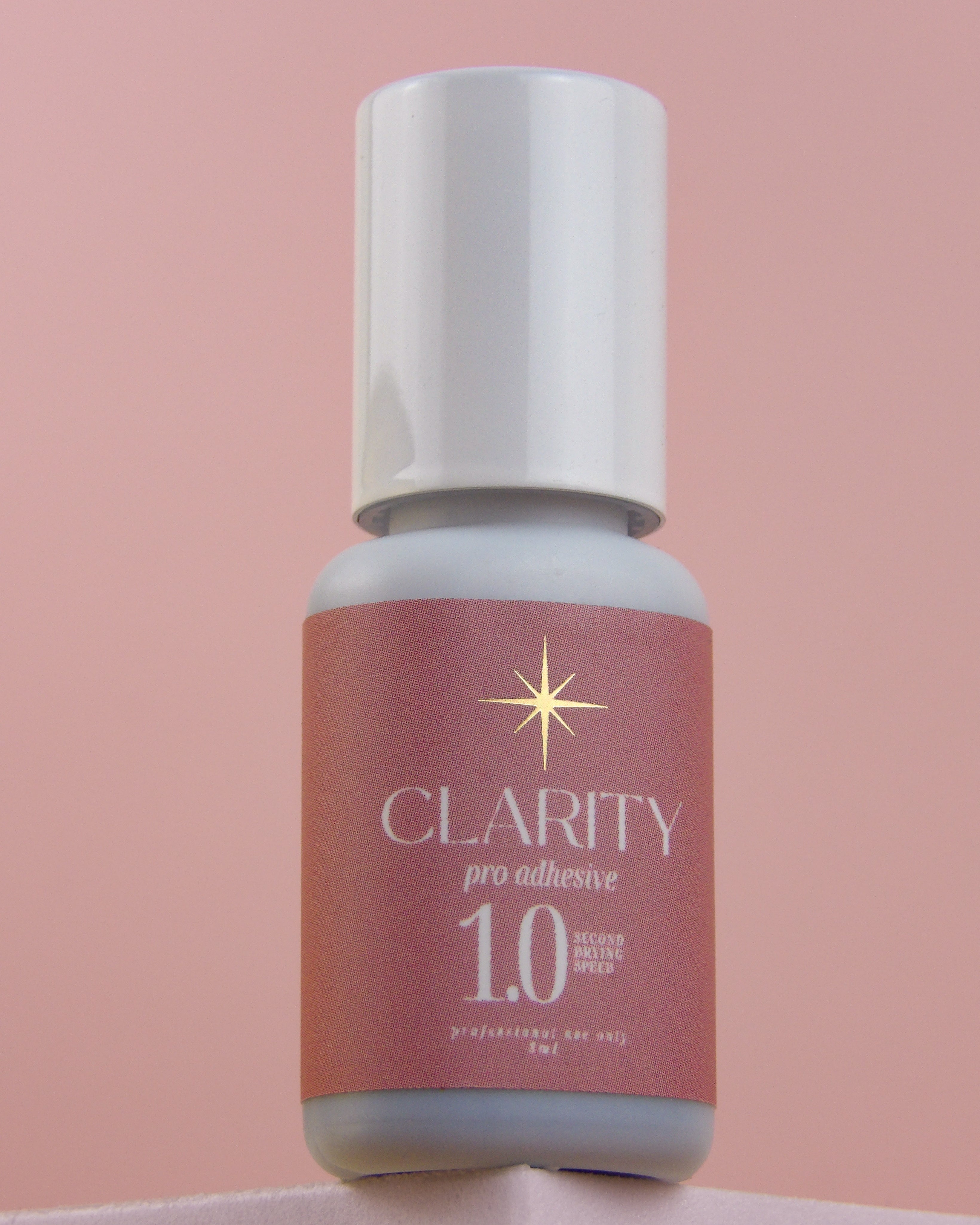 Bottle of Clarity pro adhesive 1.0 on a pink background
