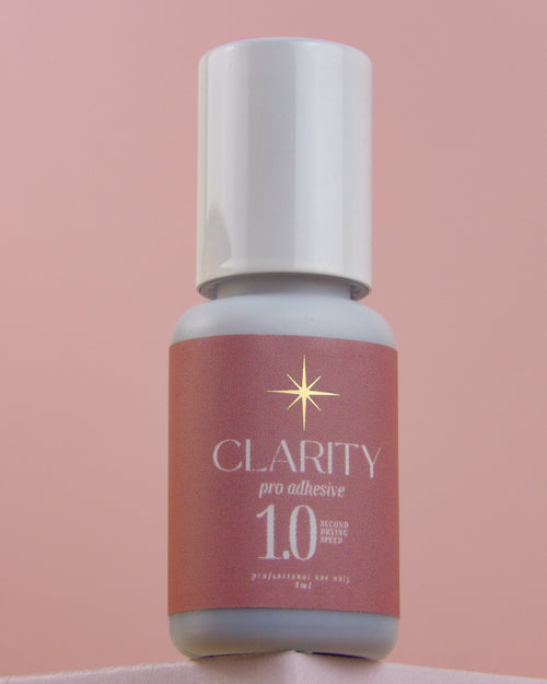 Bottle of Clarity pro adhesive 1.0 on a pink background