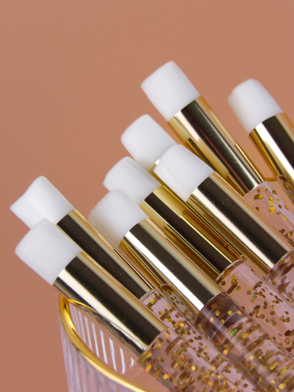 Set of cleanse brushes with gold applicators on a brown background