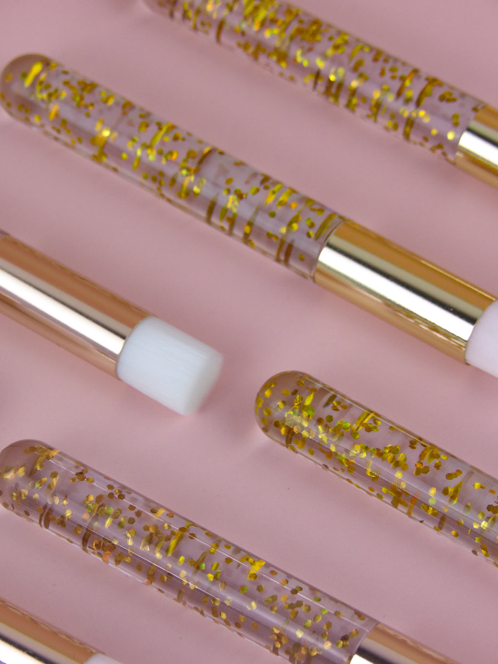 Set of cleanse brushes with gold glitter on a pink background