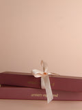Two stacked pink boxes with a white ribbon on a beige background