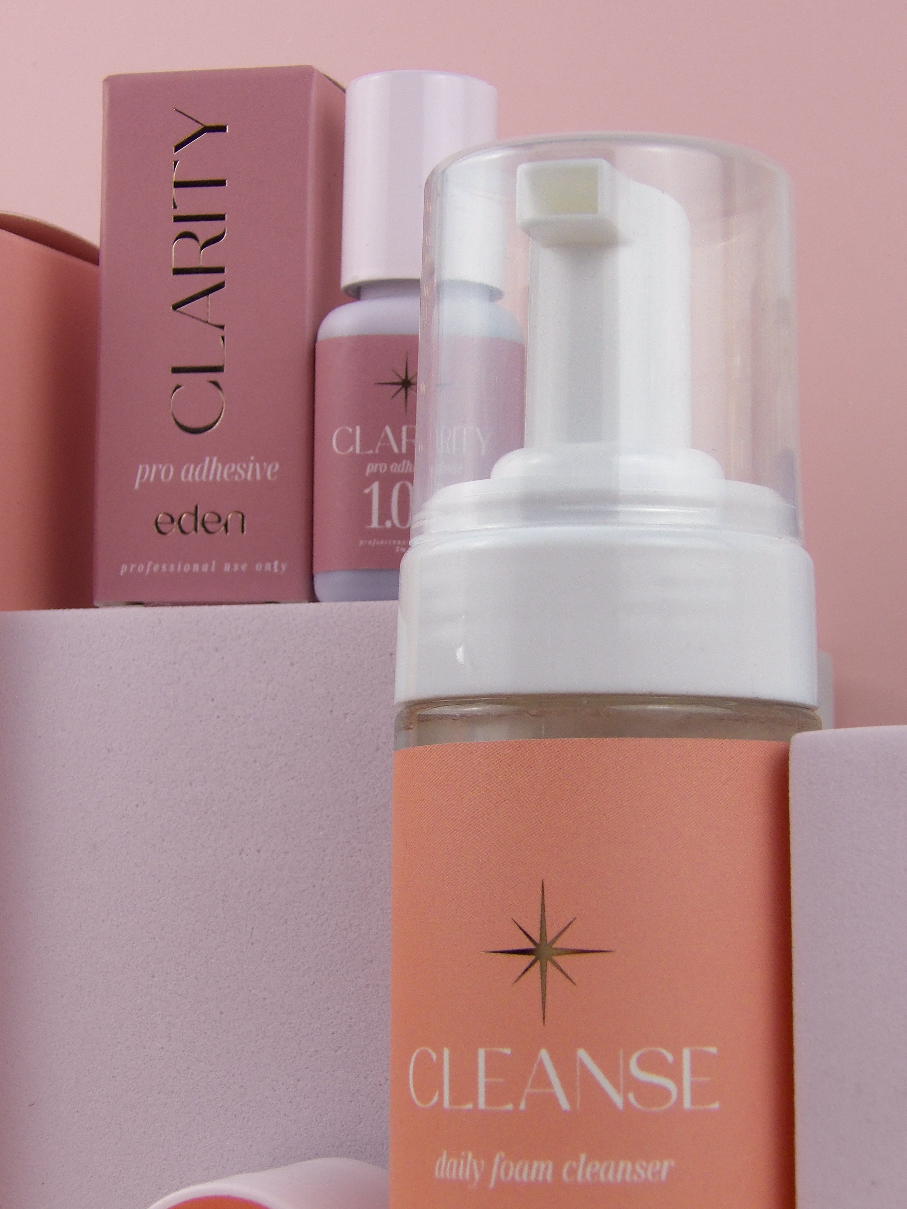 Foam cleanser bottle with 'Clarity' and 'Eden' products on a pink background