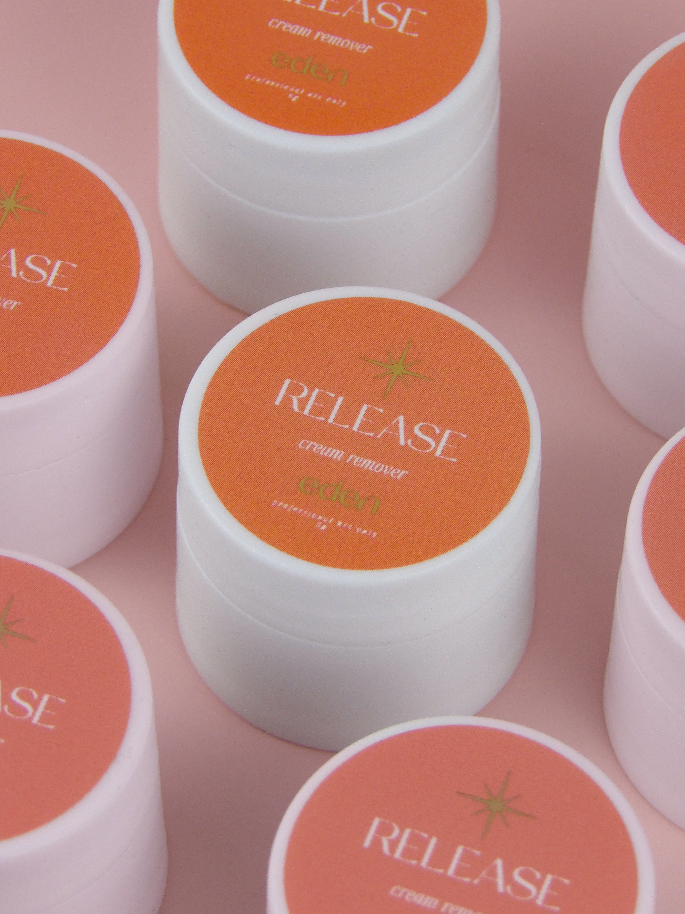 Multiple jars of 'Release' cream remover on a pink background
