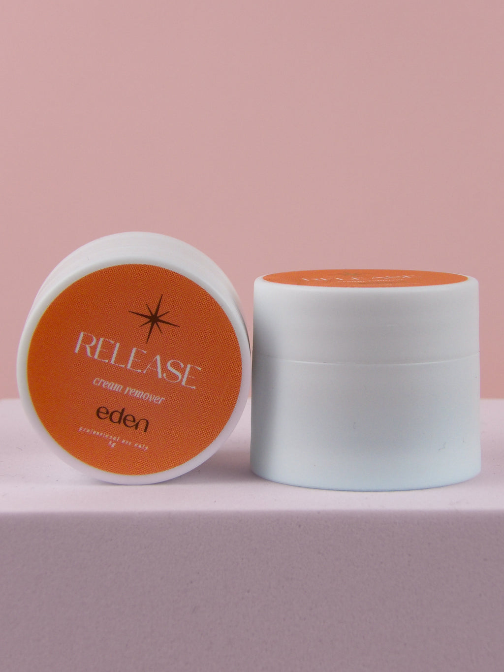 Two containers of 'Release' cream remover by 'Eden' on a pink background