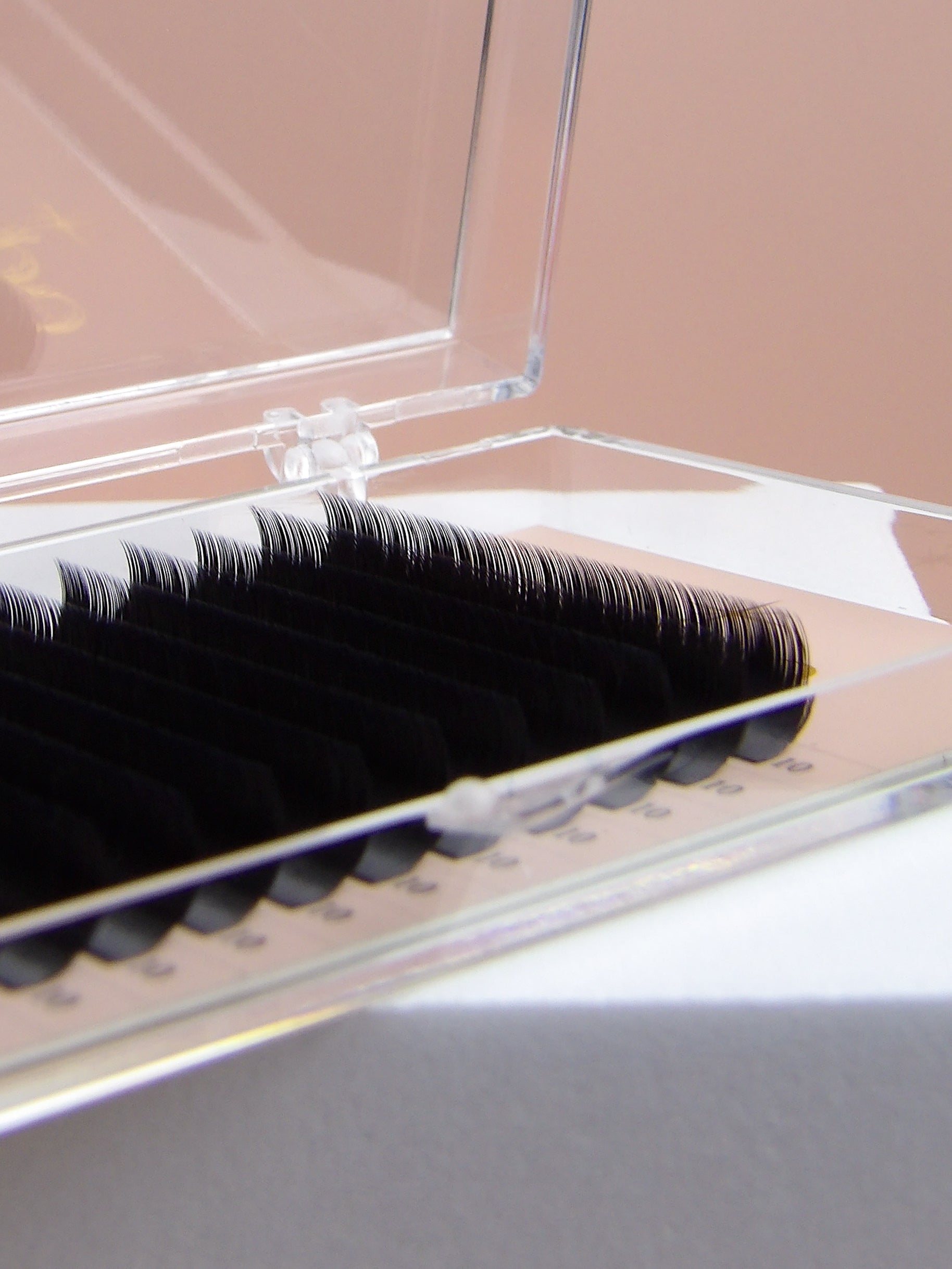False eyelashes in an open clear case on a neutral background