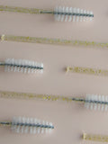Set of spoolie brushes with different bristle patterns on a beige background